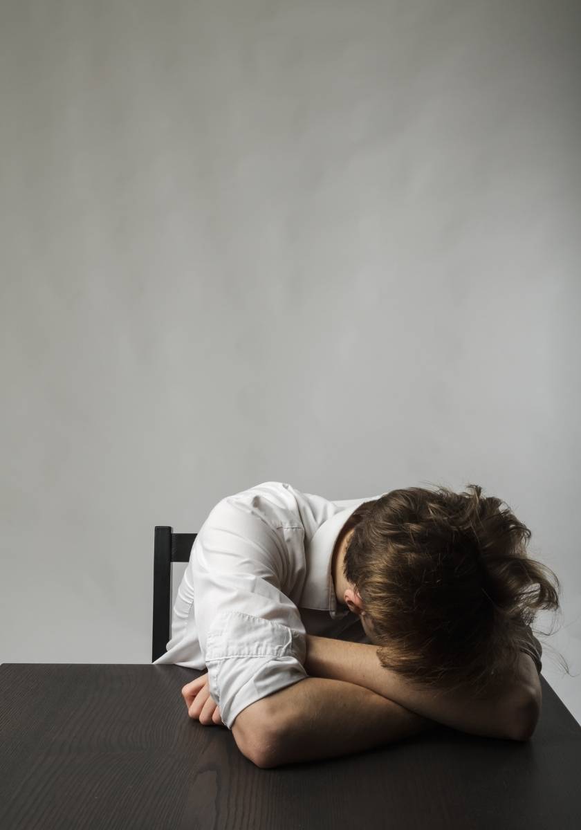 Tired person resting their head against a gray wall