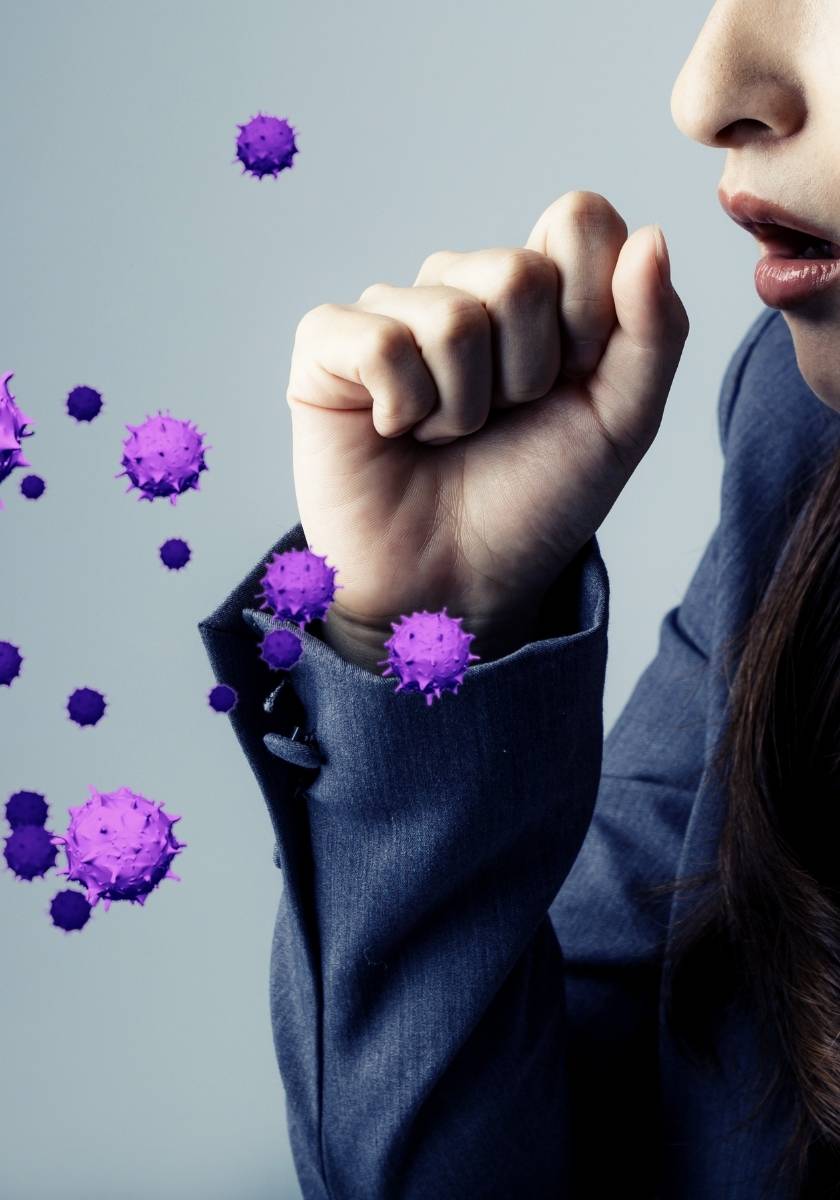Person coughing into a fist near illustrated virus particles