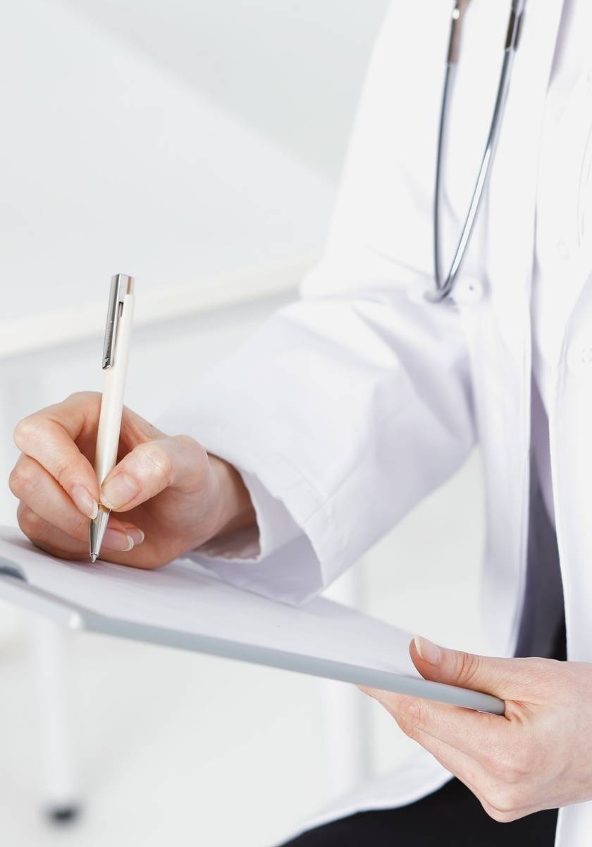 Doctor in a white coat holding a pen and clipboard