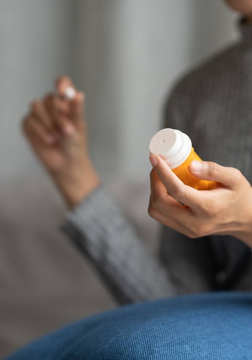 Person holding a white supplement bottle near a window